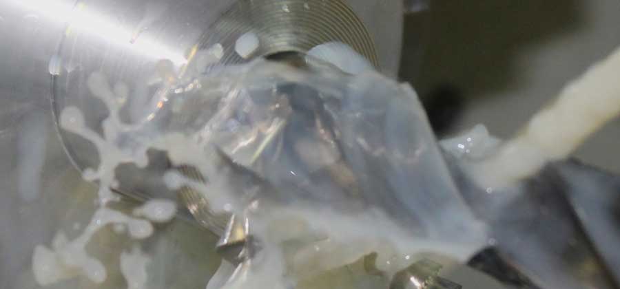 close up of water being sprayed on to a drill bit while drilling into steel
